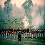 Many continental soldiers drilling and firing on the grassy fields of the grand parade.